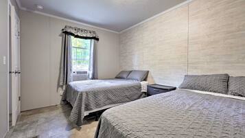 Un dormitorio con dos camas, una ventana con cortinas y una pared de madera.