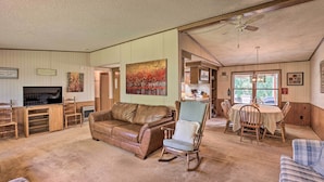 A spacious living room with a brown leather sofa, a rocking chair, and a dining table with chairs. There is a television and a painting on the wall. - Charming Burdett Home With Grill, Gazebo + Yard (Burdett)