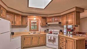 A kitchen with wooden cabinets, a white refrigerator, a stove, and a dishwasher. - Charming Burdett Home With Grill, Gazebo + Yard (Burdett)