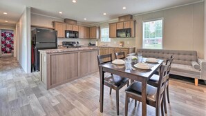 Une cuisine moderne avec des meubles en bois, un îlot central et un coin repas agrémenté d’un canapé gris.