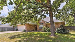 A residential house with a brick exterior, a garage, and a well-maintained lawn.