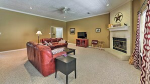 A living room with a brown leather sofa, a black coffee table, a fireplace, and a ceiling fan.