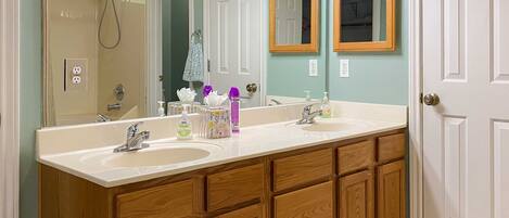 A bathroom with two sinks, wooden cabinets, a shower, and two mirrors.