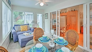A dining area with a glass table set for four, surrounded by wicker chairs.