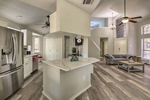 A spacious kitchen with a central island, a dining area with a sofa, and a living room with a fireplace. - Convenient Allen Retreat, 2 Mi to Downtown! (Allen)