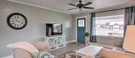 A living room with a sofa, a coffee table, a television on a stand, and a ceiling fan.