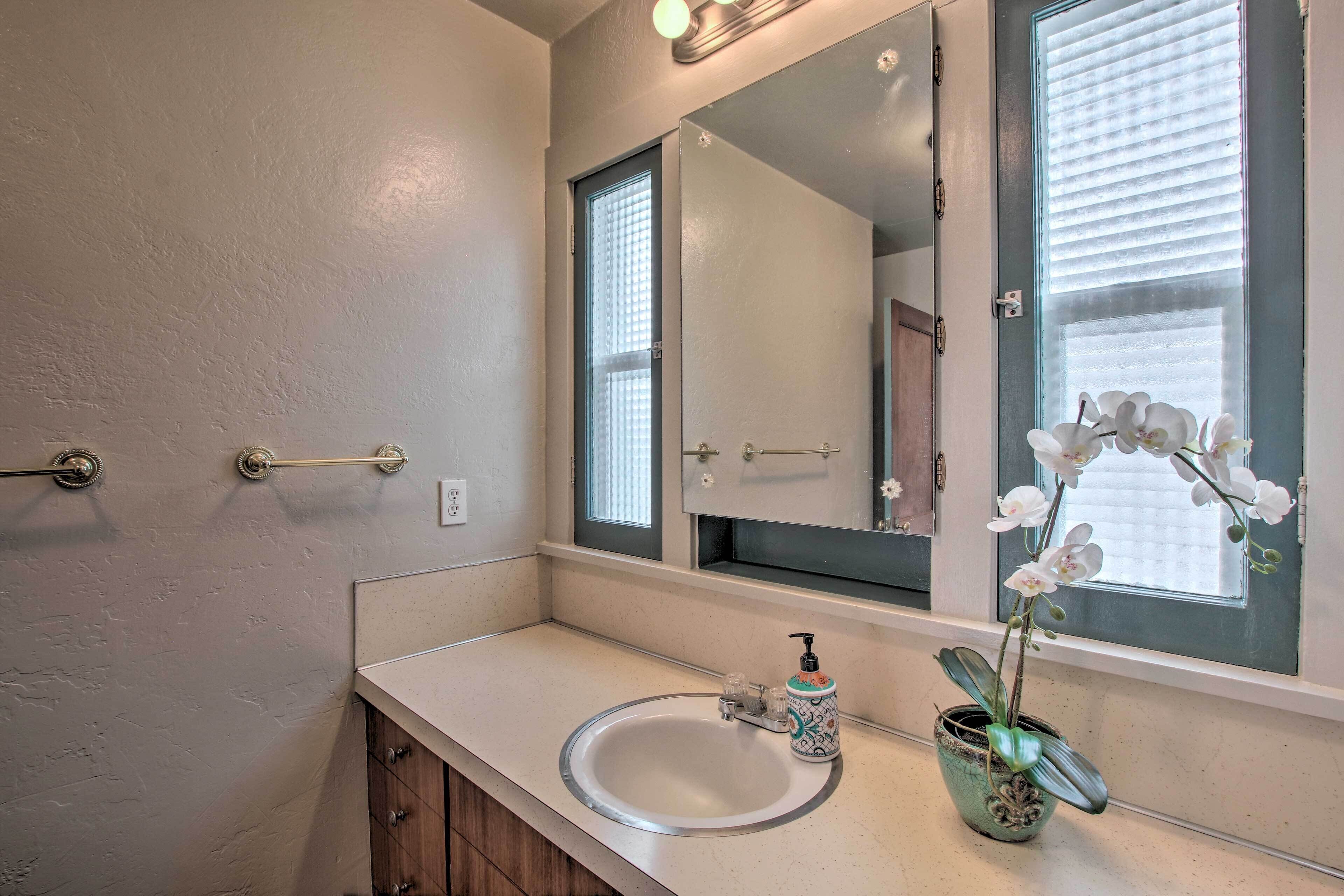 Une salle de bain avec un grand miroir, un lavabo et une orchidée en pot.
