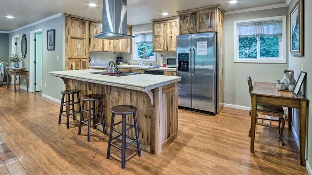 Una cocina moderna con armarios de madera, un refrigerador de acero inoxidable y una isla grande con taburetes.