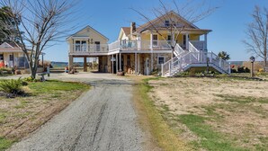A large two-story house with a porch and a staircase leading to the second floor. - Welcoming Cottage w/ Outdoor Pool & Water Views! (White Stone)