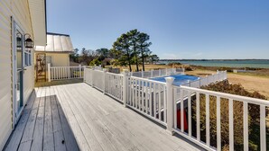 A wooden deck with a pool, white railings, and a view of the beach and ocean. - Welcoming Cottage w/ Outdoor Pool & Water Views! (White Stone)