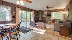 A cozy living room with a fireplace, a ceiling fan, and a dining area with chairs and a table. - Cozy Adirondacks Cabin: Walk to Lake Eaton! (Jay)