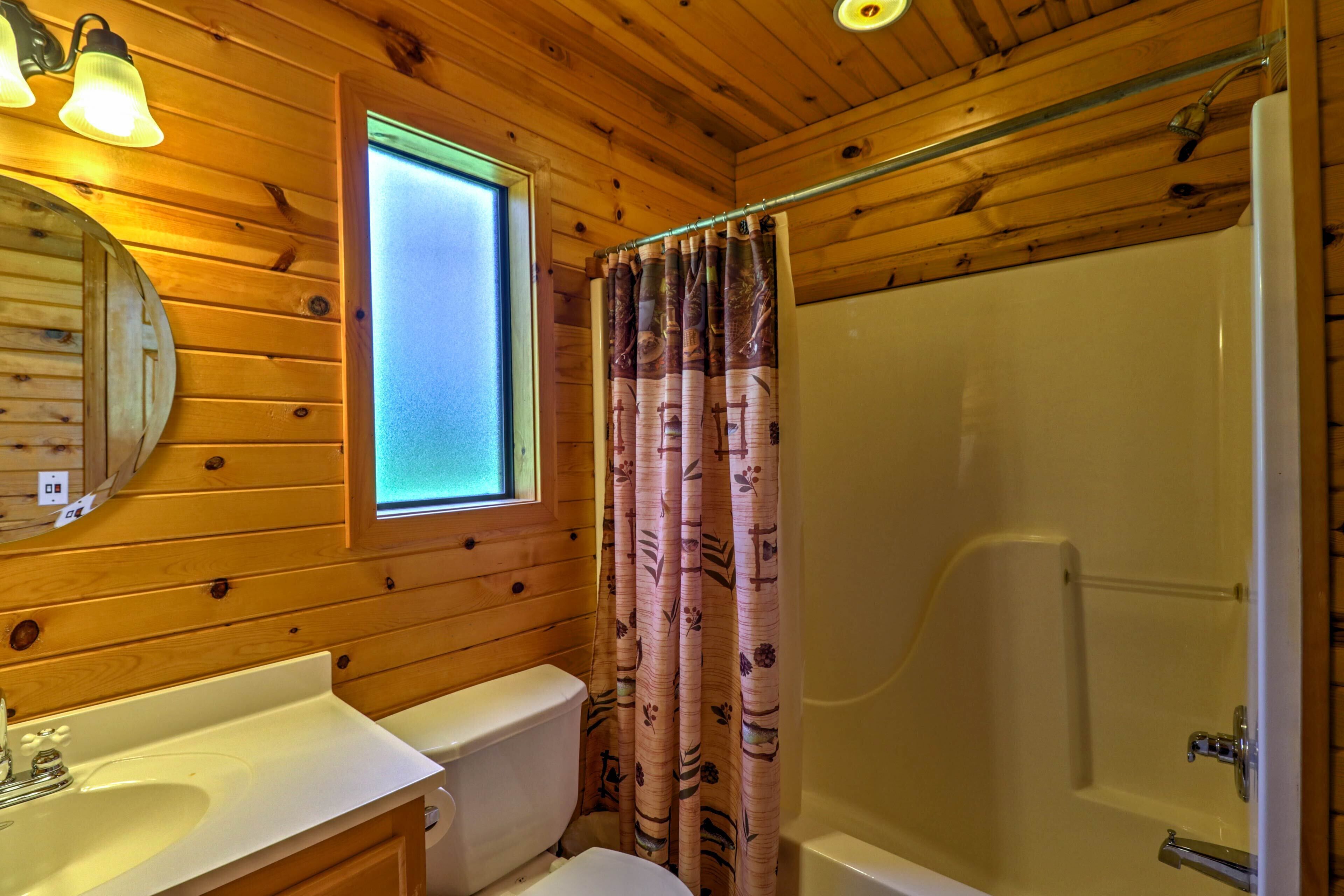 A wooden cabin bathroom with a sink, toilet, and shower.