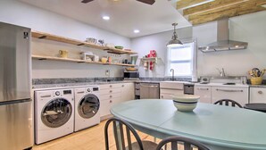 A modern kitchen with built-in appliances, wooden shelves, and a dining area with a table and chairs. - 'cora's Cottage' Near Chesapeake Bay Access! (Harborton)
