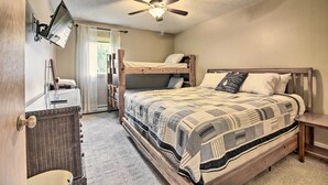 Ein Schlafzimmer mit einem Etagenbett, einem flachbildfernseher an der Wand, einem Deckenventilator und einem Fenster mit Vorhängen.