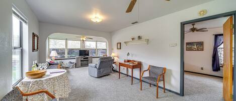 A spacious living room with a ceiling fan, a dining area with a table and chairs, and a kitchen in the background.