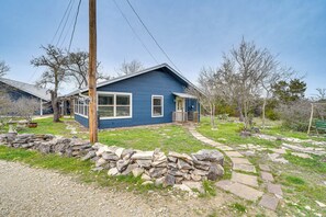 A single-story blue house with a stone pathway leading to the front door. - Cozy Kerrville Guest Cottage Near Guadalupe River! (Kerrville)