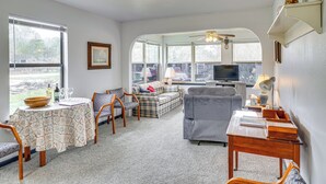 A cozy living room with a sofa, a dining table with chairs, a television, and a window with a view of the outdoors. - Cozy Kerrville Guest Cottage Near Guadalupe River! (Kerrville)