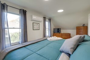 A bedroom with a bed, a dresser, a television, and an air conditioning unit. - Cozy Historic Wakefield Home Close to Beaches (South Kingstown)