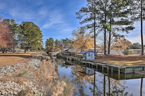 A calm river with a wooden dock, surrounded by trees and small buildings. - 'cozy Cottage' w/ Shared Dock on Dawson Creek (Oriental)