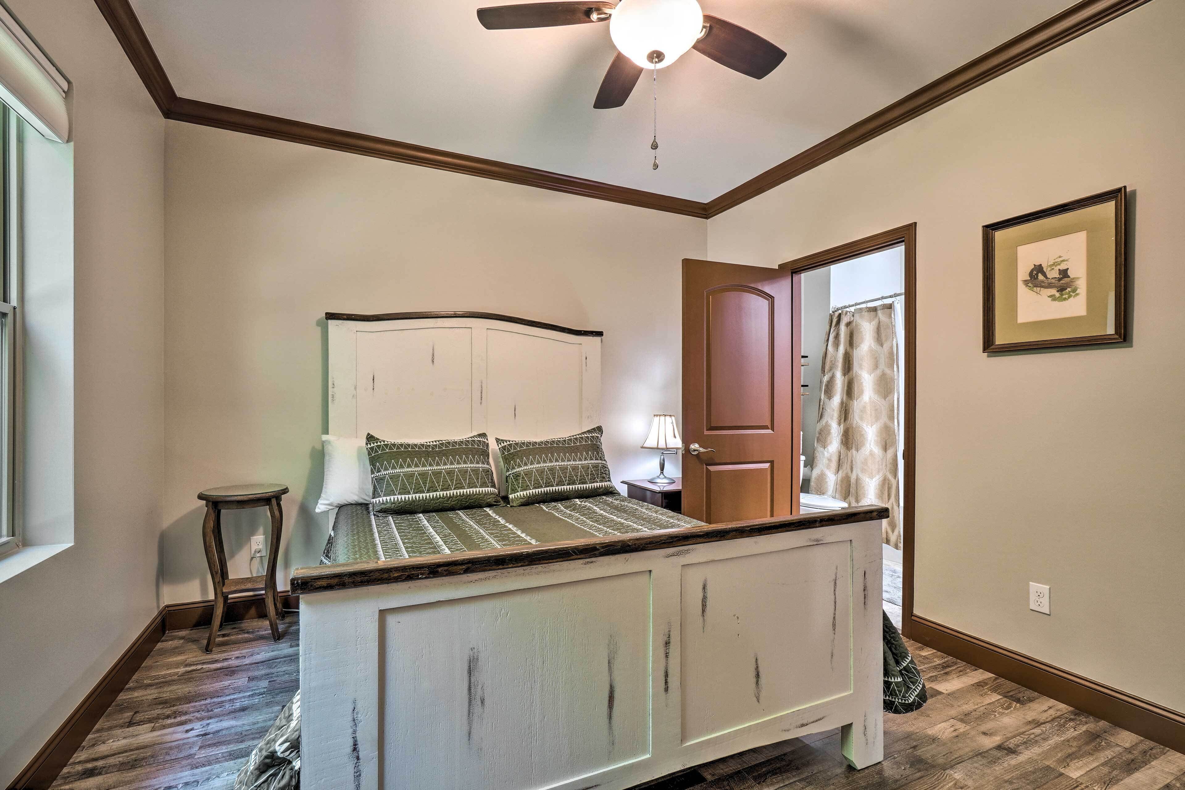 A bedroom with a bed, a ceiling fan, and a door leading to another room.