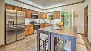 A modern kitchen with wooden cabinets, stainless steel appliances, and a central island with bar stools. - Cozy Townsend Condo, Resort-style Amenities! (Townsend)