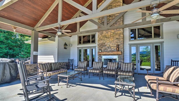 An outdoor patio with multiple seating areas, a stone fireplace, and a ceiling fan. - Cozy Townsend Condo, Resort-style Amenities! (Townsend)