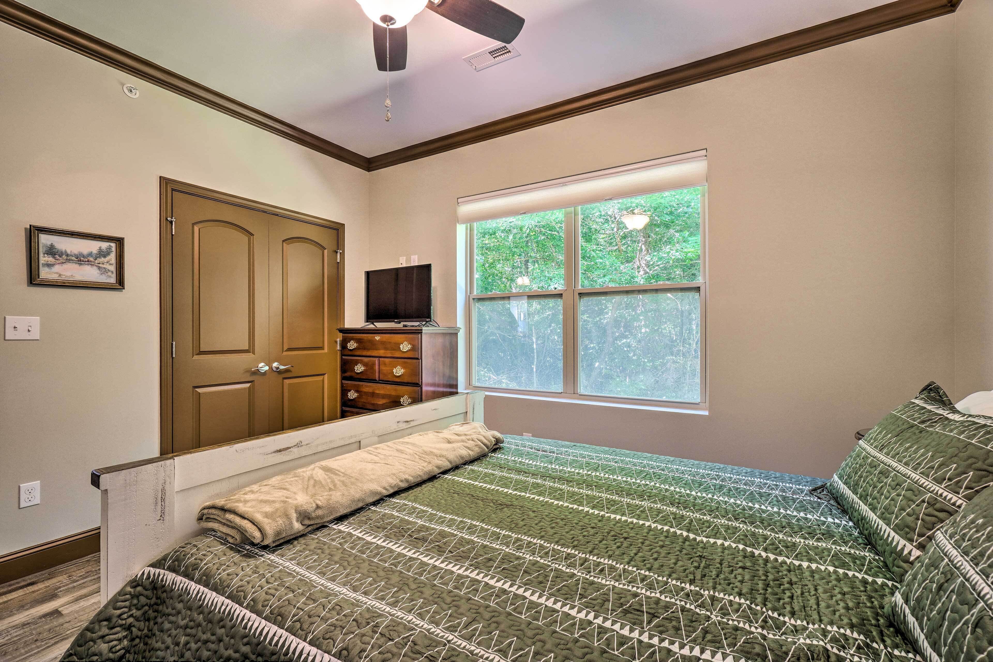 A bedroom with a bed, a window with blinds, a ceiling fan, and a door.