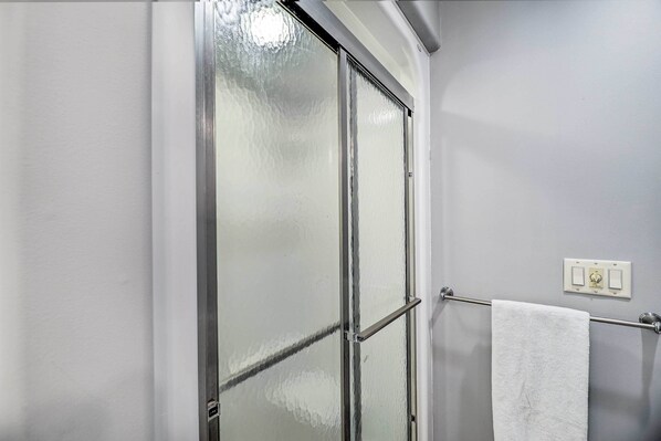 A bathroom with a frosted glass shower door, a towel rack with a white towel, and a light switch on the wall. - Cozy Whitehall Hideaway w/ Hot Tub + Chiminea! (Whitehall)