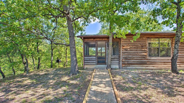 A wooden cabin with a gravel path leading to the entrance, surrounded by trees.