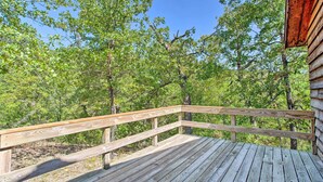 A wooden deck with a railing overlooking a forested area.