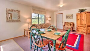 A dining area with a wooden table, green chairs, and a red and blue rug.