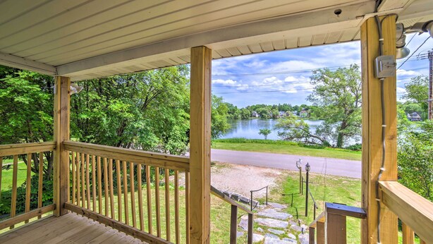 A wooden deck with a view of a lake and a road. - Cozy Ishpeming Cottage w/ Lake & Park Views! (Ishpeming)
