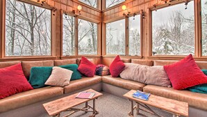 A cozy corner with a leather sofa, red and green pillows, and two wooden tables with books. - Walk to Ski Trails: Ludlow Home on Okemo Mountain! (Ludlow)