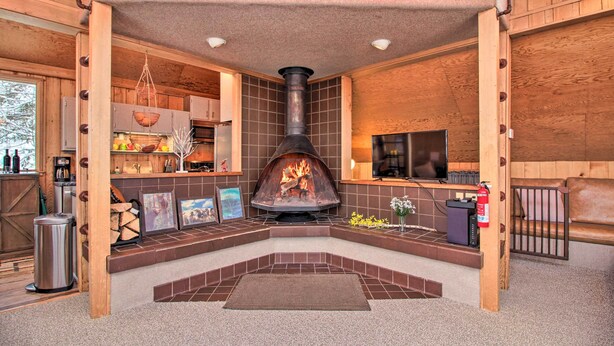 A cozy cabin interior with a fireplace, wooden walls, and a dining area. - Walk to Ski Trails: Ludlow Home on Okemo Mountain! (Ludlow)
