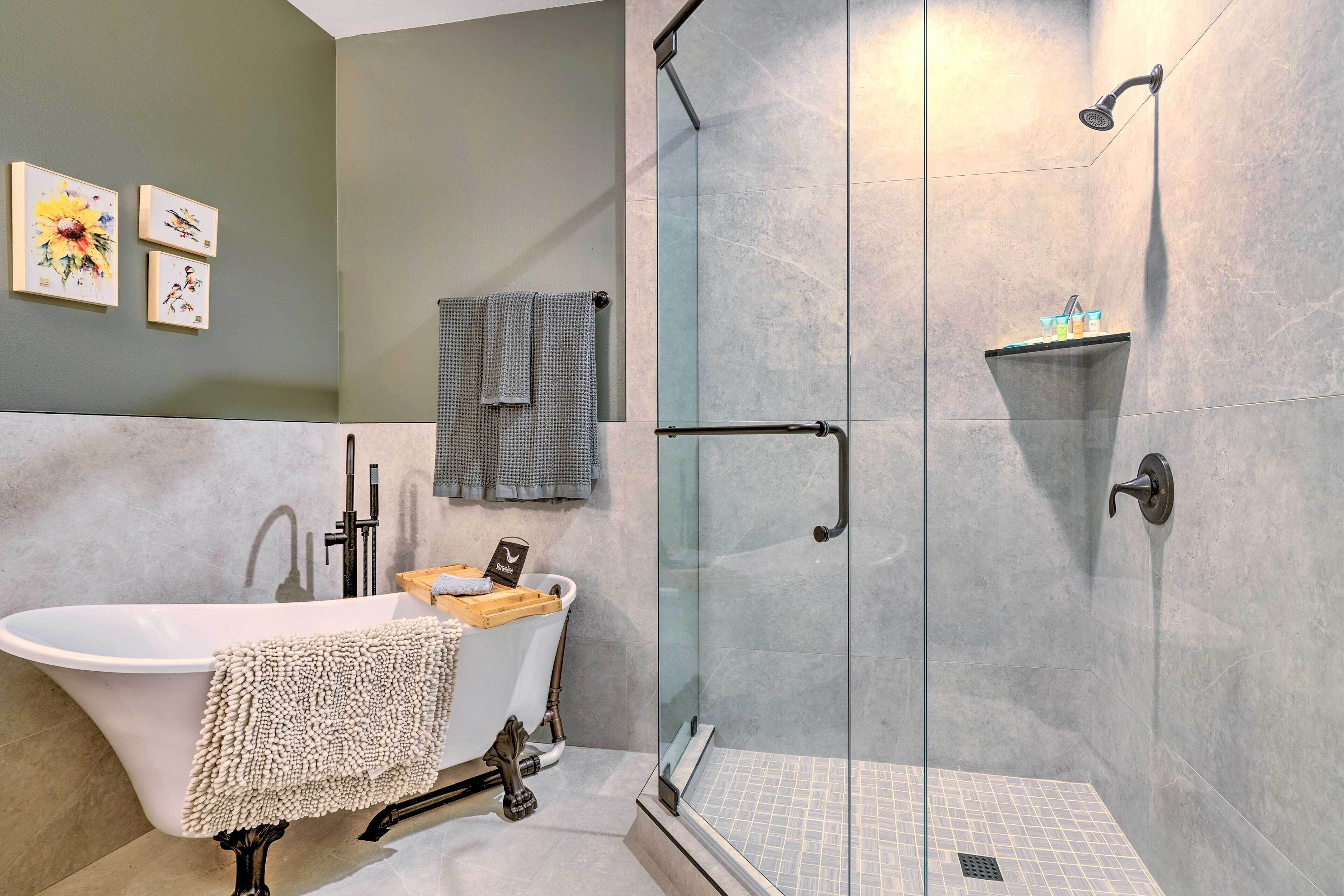 Een moderne badkamer met een vrijstaand bad, een douche met glazen wand en een betegelde vloer.