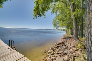 A wooden pier extending into a calm lake, surrounded by trees and rocks.