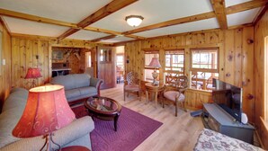 L’intérieur d’un chalet accueillant, avec un canapé, des fauteuils, une table et un téléviseur.
