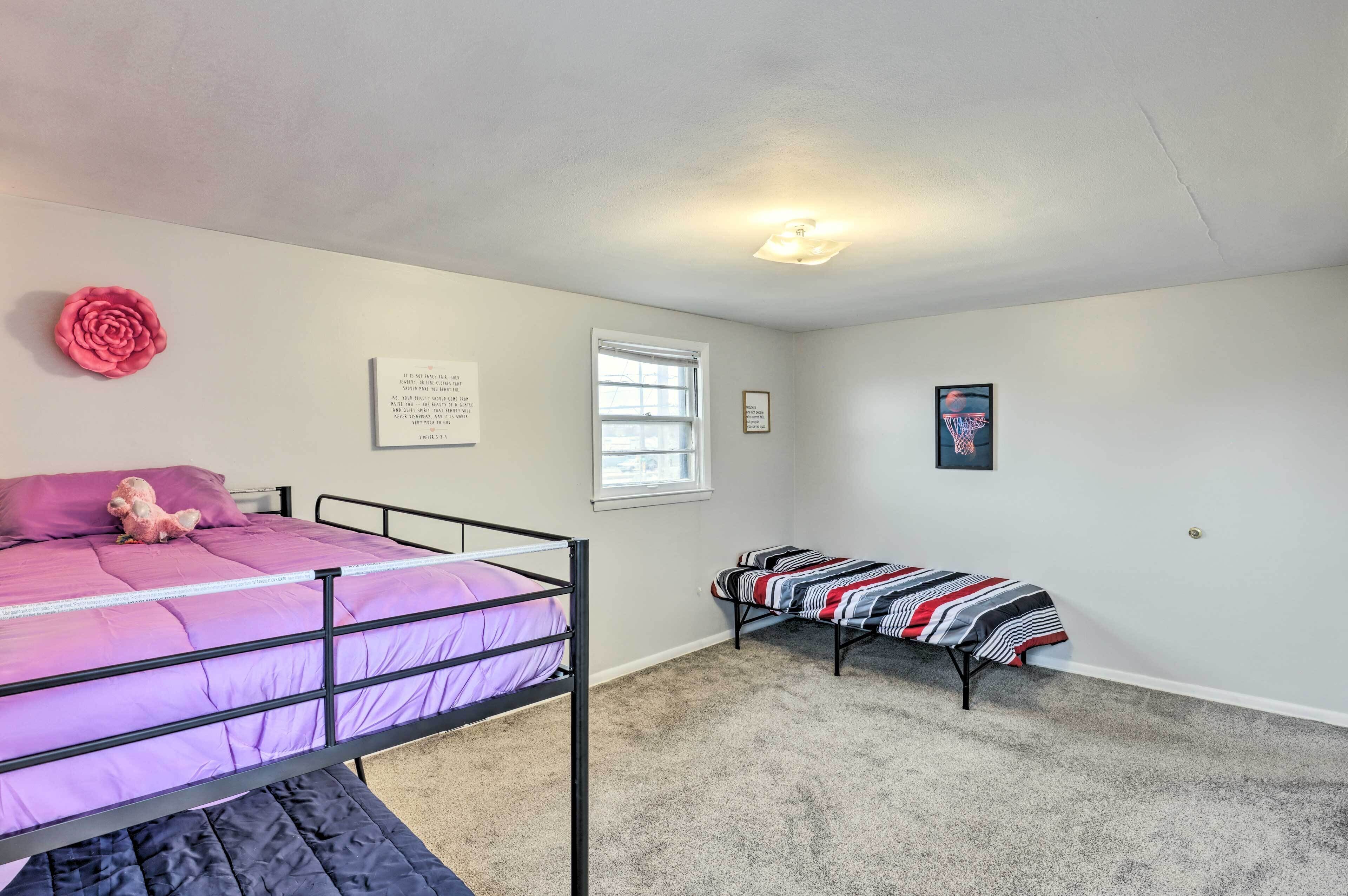 A bedroom with a bunk bed, a single bed, a window, and a basketball hoop.