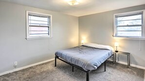 A bedroom with a bed, two bedside tables, a nightstand, and a ceiling light. - Cozy Milwaukee Home: 3 Mi to Whitefish Bay! (Milwaukee)