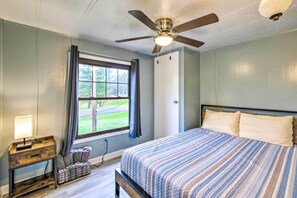 A bedroom with a bed, a desk, a window with curtains, a ceiling fan, and a view of the outdoors. - Cozy Sherrodsville Home: Walk to Lake Atwood! (Sherrodsville)