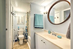 A bathroom with a toilet, sink, mirror, and shower curtain. - Cozy Sherrodsville Home: Walk to Lake Atwood! (Sherrodsville)