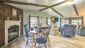 A cozy living room with a fireplace, a dining table with chairs, a sofa, and a television. - Cozy Sherrodsville Home: Walk to Lake Atwood! (Sherrodsville)