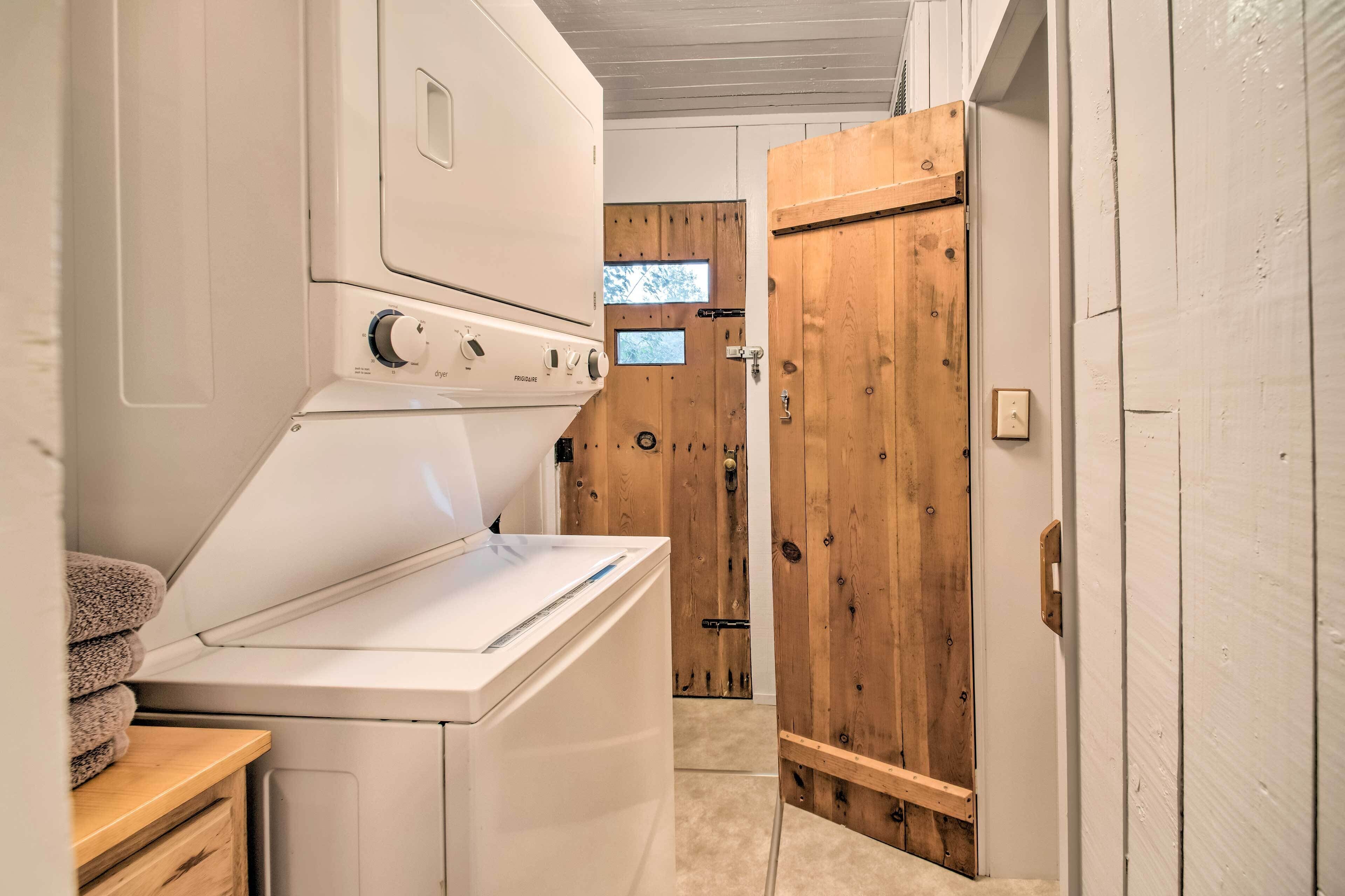 A laundry room with a front-loading washer and dryer, wooden doors, and a small window.