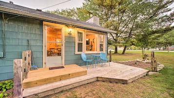 Una casa con terraza de madera, un porche y un pequeño espacio al aire libre con dos sillas.