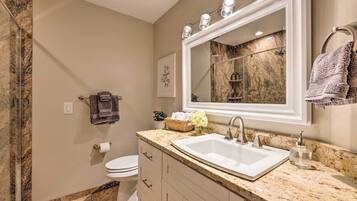 A bathroom with a marble sink, a large mirror, and a towel rack.