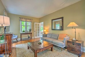 A living room with a sofa, coffee table, lamp, and a wooden chest of drawers.