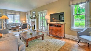 A spacious living room with a sofa, coffee table, TV, and a fireplace. - Elegant Charles Town Home: Grill, Walk Dtwn! (Charles Town)