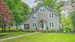 A two-story house with a front porch, a chimney, and a well-maintained lawn. - Elegant Charles Town Home: Grill, Walk Dtwn! (Charles Town)