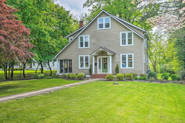 A two-story house with a front porch, a chimney, and a well-maintained lawn.