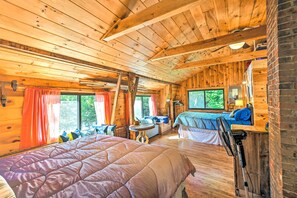 A cabin-style room with a large bed, a smaller bed, and a desk with a chair. - Dreamy Bucksport Hideaway on Freshwater Pond! (Bucksport)